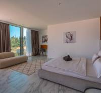 Schlafzimmer in einer Villa mit großen Fenstern und Marmorboden, mit stilvollen Möbeln.