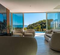 Das Innere der Villa mit großen Fenstern, Blick auf das Grün und den Pool.