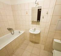 Badezimmer einer Zweizimmerwohnung mit klassischer Badewanne und Fliesen in neutralen Tönen.