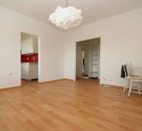 Ein Zimmer mit einem Holzboden, weißen Möbeln und einer roten Küchenwand.