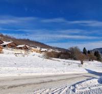 Verschneite Landschaft mit Holzhütten auf den Erholungsgrundstücken bei der Straße Fongrub in Mýto pod Ďumbierom.