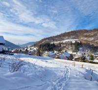 Schneebedeckte Wohnbaugrundstücke in Mýto pod Ďumbierom bieten ein Winterpanorama der Berge.