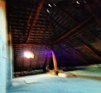 Dachboden in einem Einfamilienhaus mit Holzbalken und Fenster.