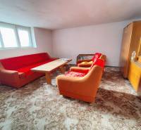 Wohnzimmer in einem Einfamilienhaus mit einem orangefarbenen Sofa, einem Holztisch und einer Vitrine.