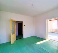 Innenraum eines Einfamilienhauses mit offenen Türen, weißen Wänden und grünem Boden.