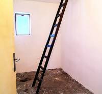 Dachboden in einem Einfamilienhaus mit einer Leiter, die zu einer Öffnung in der Decke führt.