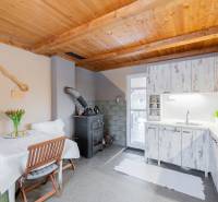 Küche in einer Hütte mit Holzdecke, Ofen und weißen Möbeln.