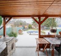 Ein Holzunterstand bei einer Hütte in Handlová, mit Blick auf den verschneiten Garten und die Zäune.