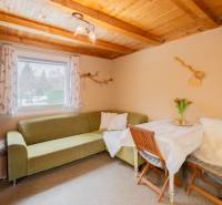 Das Innere der Hütte mit einer Eckcouch, einem Tisch und einer Holzdecke.