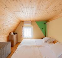 Ein Dachzimmer in einer Hütte mit einer Holzdecke und einem Bett, Boden mit Holzdekor.