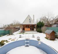 Ein verschneiter Garten mit einer Hütte in Handlová und einem leeren Pool im Vordergrund.