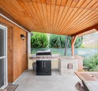 Holzverkleidung und Grill auf der Terrasse der Hütte in Handlová, neben grünen Sträuchern.