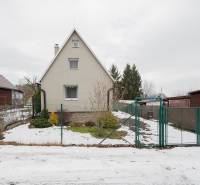 Ein Haus in Handlová mit etwas Schnee im Hof, umgeben von Grün und einem Zaun.