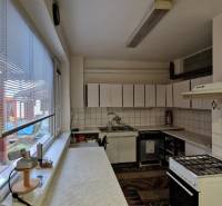 Küche in einem Einfamilienhaus mit Geräten, Fliesen und einem Fenster mit Blick auf die Terrasse.