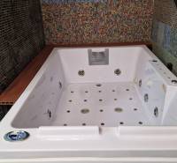 Im Badezimmer eines Einfamilienhauses befindet sich eine große Whirlpool-Badewanne, die mit bunten Mosaikfliesen verziert ist.