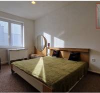 Schlafzimmer mit Doppelbett, grüner Decke, Nachttisch und Spiegel in einem Einfamilienhaus.