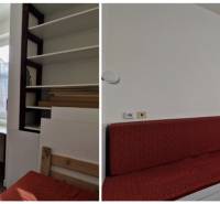 In einem Einfamilienhaus gibt es weiße Schränke, einen Arbeitstisch und ein rotes Sofa.