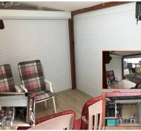 Sommerterrasse eines Einfamilienhauses mit Sitzbereich und Boden in Holzoptik.