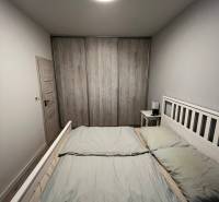 Helles Schlafzimmer in einer 2-Zimmer-Wohnung mit geräumigem Bett und Schrank in Holzoptik.