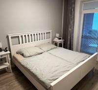 Schlafzimmer mit Holzboden und einfachem Bett in einer Zweizimmerwohnung.