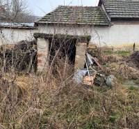 Ein verlassenes Gebäude auf einem Grundstück in Dubník mit ungepflegter Umgebung und alten Dächern.