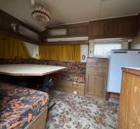 Innenraum eines Wohnbereichs mit Teppichboden, Sitzgarnitur und Tisch.