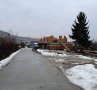 Bauplatz eines Einfamilienhauses in Višňové in der Višňová-Straße mit verschneiter Umgebung und einem Baum.