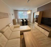 Wohnzimmer mit Holzboden, großem Sofa und Esstisch in einer 3-Zimmer-Wohnung.