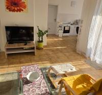 Wohnzimmer in einem Einfamilienhaus mit Sofa, Fernseher und Blick auf die Küche.