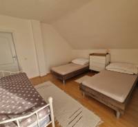 Schlafzimmer im Einfamilienhaus mit drei Betten und einem Boden in Holzoptik.