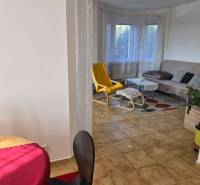 Wohnzimmer in einem Einfamilienhaus mit Fenster, gelbem Sessel und Tisch.