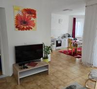 Wohnzimmer in einem Einfamilienhaus mit Fernseher, buntem Teppich und Bild an der Wand.