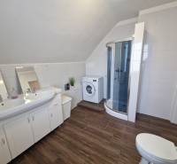 Badezimmer in einem Einfamilienhaus mit Waschbecken, Duschkabine und Boden mit Holzdekor.