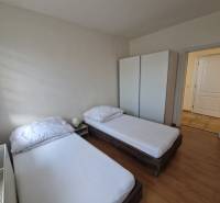 Ein Zimmer in einem Einfamilienhaus mit zwei Betten, einem Schrank und einem Boden mit Holzdekor.