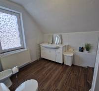 Badezimmer mit Holzboden in einem Einfamilienhaus, ausgestattet mit WC, Waschbecken und Badewanne.