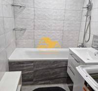 Badezimmer in einer 3-Zimmer-Wohnung mit Badewanne, Dusche und Waschmaschine auf weißen Fliesen.