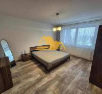 Schlafzimmer in einer 3-Zimmer-Wohnung mit Bett, Spiegel und Boden mit Holzdekor.