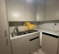 Küche in einer 2-Zimmer-Wohnung mit Marmorplatte und grauen Schränken.