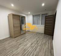 Geräumiges Zimmer mit einem Schiebeschrank und einem Boden mit Holzdekor in einer Einzimmerwohnung.