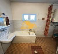 Badezimmer in einem Einfamilienhaus mit Badewanne, Waschbecken und Boiler.