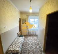 Ein Flur in einem Einfamilienhaus mit Teppichdekor und einem Tisch, Fenster am Ende des Raumes.