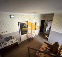 Innenraum eines Einfamilienhauses mit gemusterten Tapeten, Möbeln und Blumendekoration.