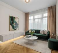 Wohnzimmer mit einem grünen Sofa, einem dekorativen Tisch und einem Boden in Holzoptik.