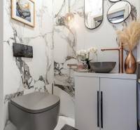 Badezimmer in einer 2-Zimmer-Wohnung mit Marmorwänden, stilvollem Waschbecken und Dekorationen.