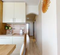 Eine Küchenzeile mit weißen Schränken und einem Boden in Holzoptik in einer 3-Zimmer-Wohnung.