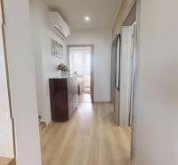 Der Flur in der 3-Zimmer-Wohnung mit einem Boden in Holzoptik, einer Kommode und einer Klimaanlage.