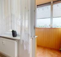Vorhänge, Fenster, Heizkörper, Balkon mit Fliesen und Boden mit Holzdekor in einer 3-Zimmer-Wohnung.