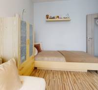 Ein Zimmer mit einem Bett, einem Schrank und einem Boden in Holzoptik in einer 3-Zimmer-Wohnung.