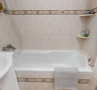 Ein Badezimmer mit Badewanne und Waschbecken in einer 3-Zimmer-Wohnung, gefliest mit hellen Fliesen.