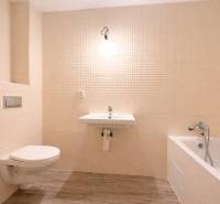 Badezimmer in einem Einfamilienhaus mit Badewanne, Waschbecken und Boden mit Holzdekor.